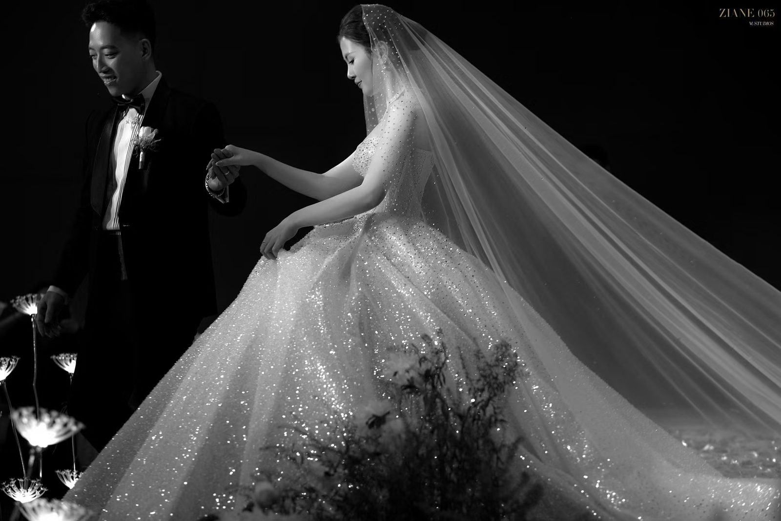 Ảnh đen trắng cô dâu váy xòe đính pha lê lấp lánh và voan dài bên chú rể vest đen