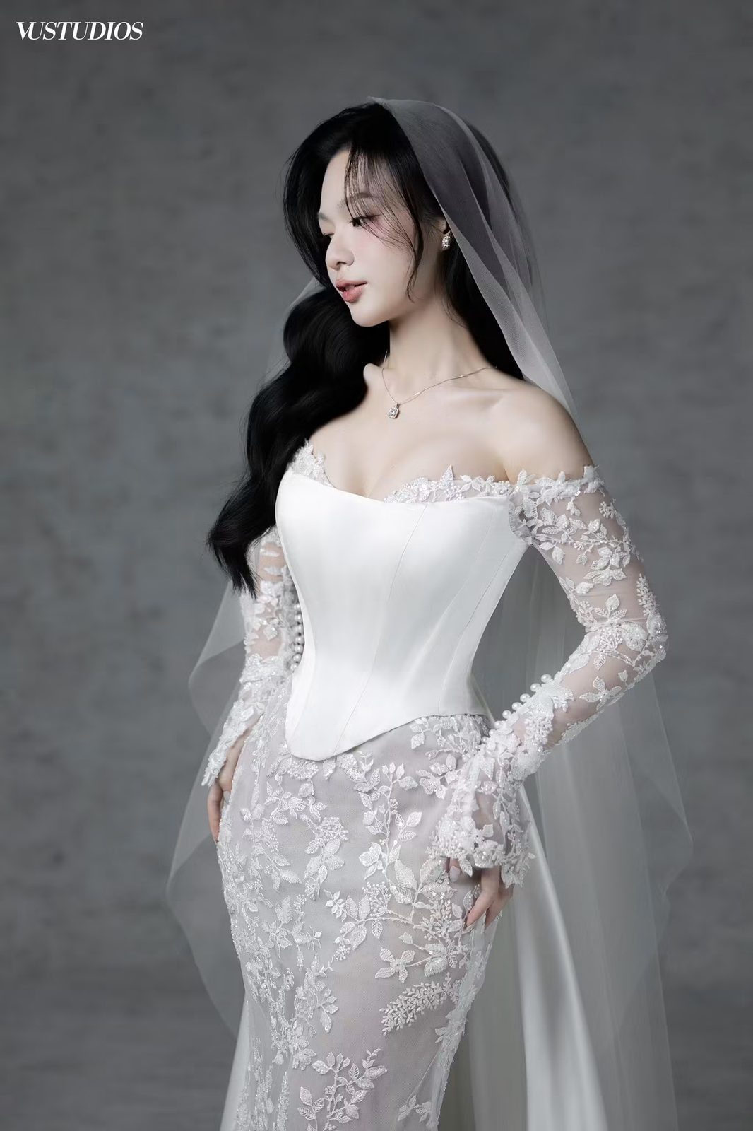 Cô dâu váy cưới corset cúp ngực tay ren dài và voan trên nền xám, tóc xõa sóng