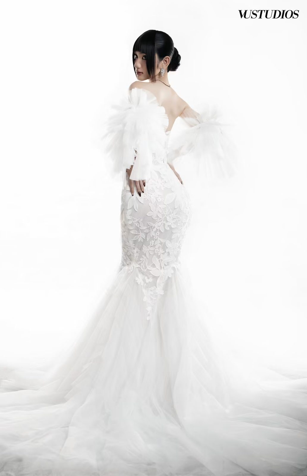 Cô dâu quay lưng váy cưới ren đuôi cá tùng tulle xòe và tay bèo lông trên nền trắng