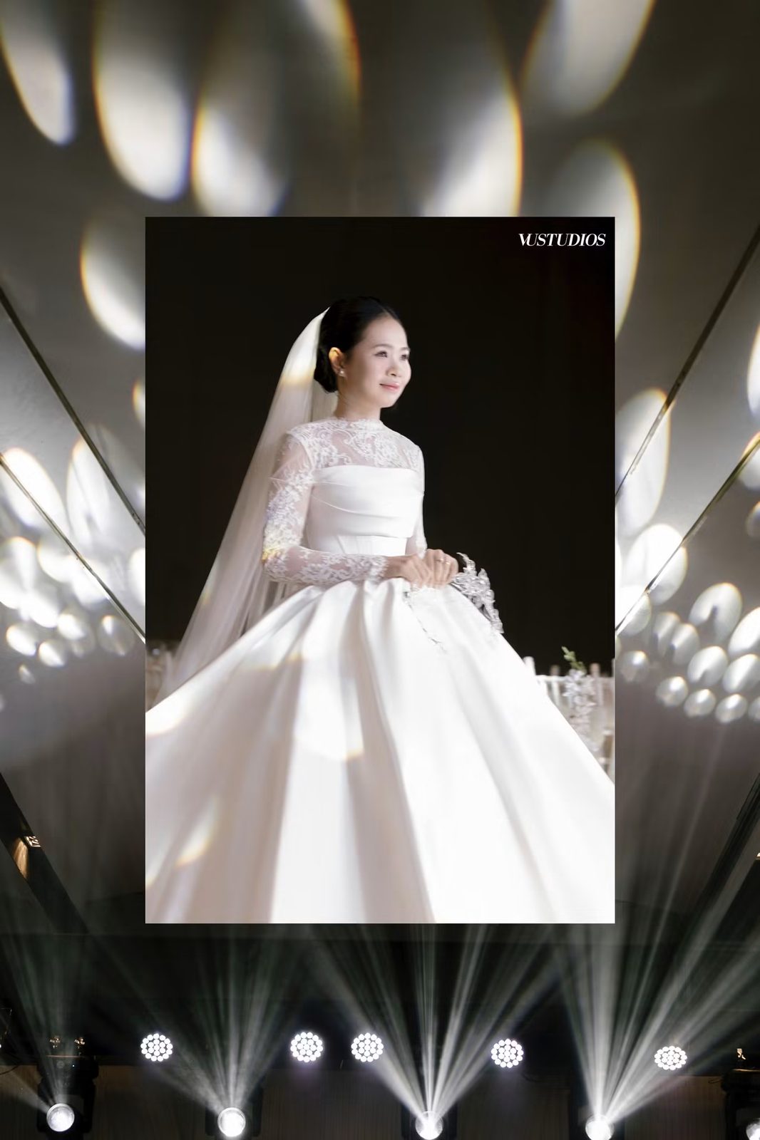Cô dâu váy cưới tay ren dài chân váy satin xòe trước nền đèn spotlight sân khấu